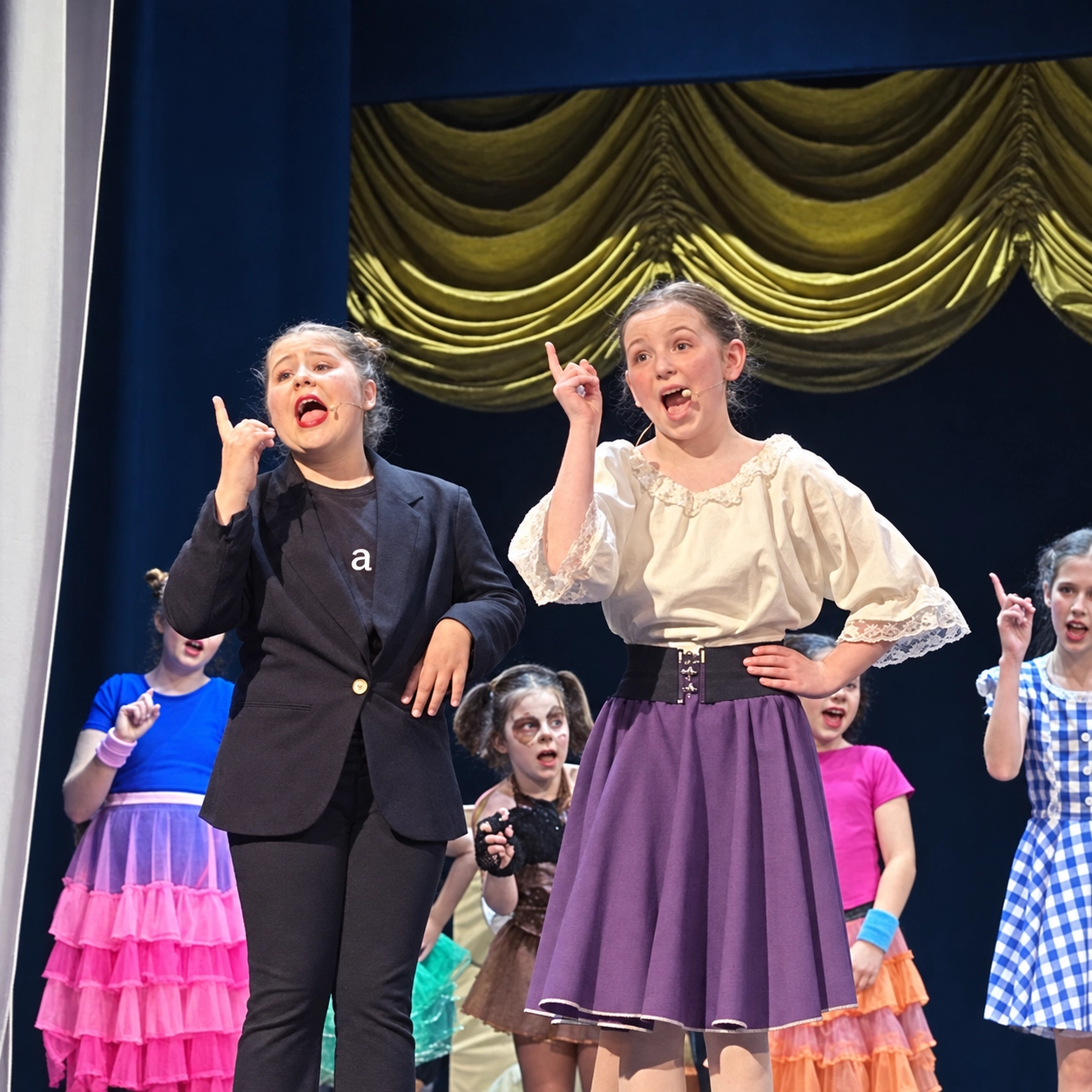 Children in colourful costumes performing on stage at AIM Theatre School